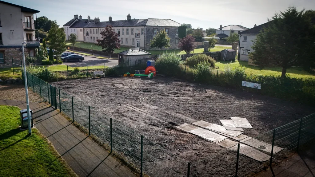 Wide view of the fenced Ballyconnell playground site and nearby homes during refurbishment